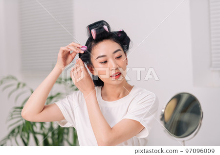 woman using hair rollers to create beautiful hairstyle on her hairdo. woman using hair rollers to create beautiful hairstyle on her hairdo. 97096009