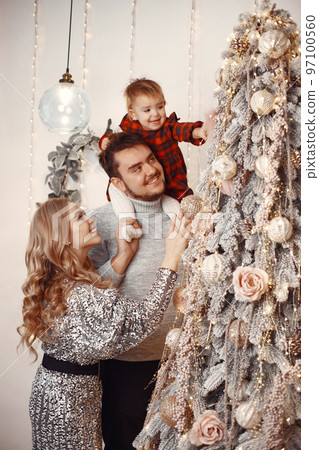 People reparing for Christmas. People playing with their daughter. Family is resting in a festive room. Child in a red dress. People reparing for Christmas. People playing with their daughter. Family is resting in a festive room. Child in a red dress. 97100560