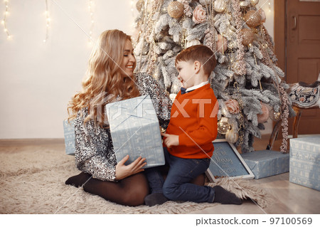 People reparing for Christmas. Mother playing with her son. Family is resting in a festive room. Child in a red sweater. People reparing for Christmas. Mother playing with her son. Family is resting in a festive room. Child in a red sweater. 97100569
