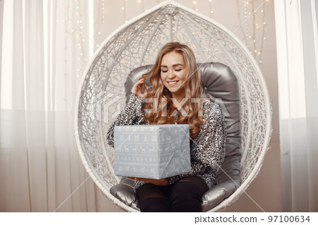 Elegant lady near Christmass tree. Woman in a room. Famale in a silver dress. 97100634