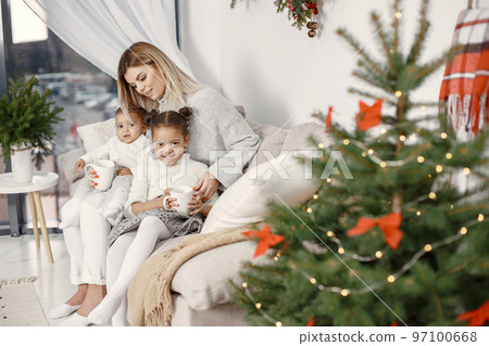 People reparing for Christmas. Mother playing with her daughters. Family is resting in a festive room. Child in a sweater sweater. People reparing for Christmas. Mother playing with her daughters. Family is resting in a festive room. Child in a sweater sweater. 97100668