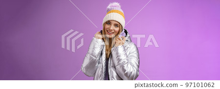 Tender feminine gentle blond girlfriend posing boyfriend take pictures ski resort holiday wearing glittering stylish jacket winter hat standing pleased purple background smiling delighted Tender feminine gentle blond girlfriend posing boyfriend take pictures ski resort holiday wearing glittering stylish jacket winter hat standing pleased purple background smiling delighted 97101062