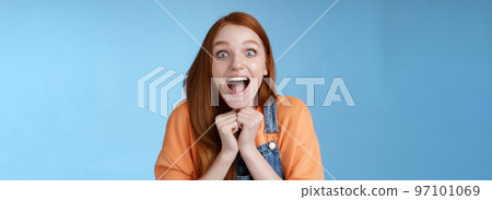 Cute redhead european girl blue eyes freckles reacting amused shocking rumor lift eyebrows drop jaw surprised smiling excited picked get role theatre play rejoicing astonished blue background 97101069