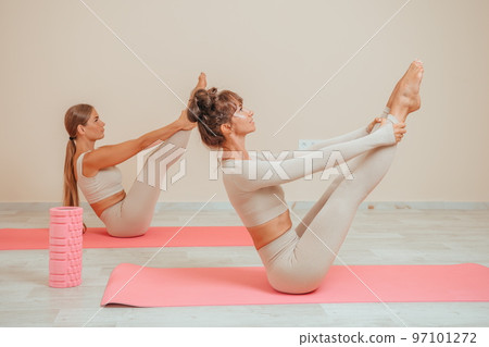 Young womans with long hair, fitness instructor in beige sportswear, preparing for stretching and pilates on yoga mat in the gym. Female fitness yoga concept. Healthy lifestyle harmony and meditation. 97101272