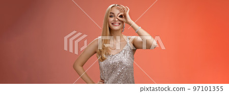 Charming elegant blond european carefree woman in silver glittering evening dress show no problem okay sign look through eye smiling delighted check out awesome promo intrigued, red background Charming elegant blond european carefree woman in silver glittering evening dress show no problem okay sign look through eye smiling delighted check out awesome promo intrigued, red background 97101355