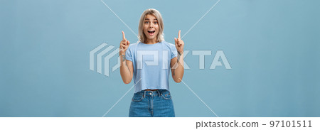 Waist-up shot of impressed enthusiastic creative blonde woman in trendy summer outfit smiling gasping being charmed and thrilled with awesome copy space pointing up over blue background Waist-up shot of impressed enthusiastic creative blonde woman in trendy summer outfit smiling gasping being charmed and thrilled with awesome copy space pointing up over blue background 97101511