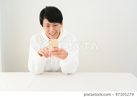 在辦公桌前操作智能手機的年輕人 在辦公桌前操作智能手機的年輕人 97105279