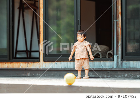 一個 2 歲的男孩在木甲板上追球 97107452
