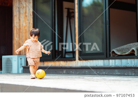 一個 2 歲的男孩在木甲板上追球 97107453