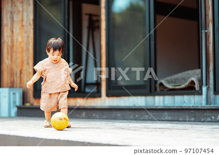 一個 2 歲的男孩在木甲板上追球 97107454