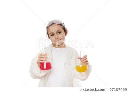 Smart primary school student, cute little girl in lab coat, posing with laboratory flasks with colorful chemical solutions, isolated white background. Chemistry Science. Education concept. Copy space Smart primary school student, cute little girl in lab coat, posing with laboratory flasks with colorful chemical solutions, isolated white background. Chemistry Science. Education concept. Copy space 97107469