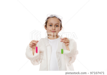 Lovely child girl, future chemist scientist in lab coat, smiles looking at camera, holding out test tubes with liquid chemical, isolated on white background. Kids learning chemistry. Education concept Lovely child girl, future chemist scientist in lab coat, smiles looking at camera, holding out test tubes with liquid chemical, isolated on white background. Kids learning chemistry. Education concept 97107471