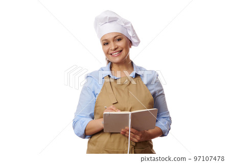 People, profession and job concept - happy smiling multi-ethnic woman waitress or pastry chef in beige apron, smiling looking at camera, holding a notepad and accepting the orders, on white background 97107478