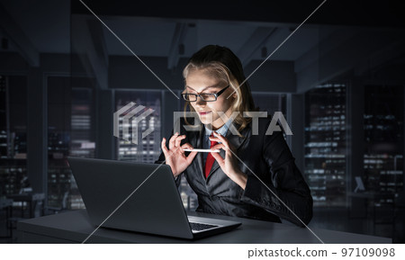 Charming businesswoman sitting at office desk Charming businesswoman sitting at office desk 97109098