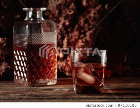 Whiskey with ice on an old wooden table. Whiskey with ice on an old wooden table. 97110196