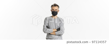 Concept of coronavirus, lifestyle and quarantine. Portrait of displeased middle-aged man in medical mask and gloves, cross arms on chest and looking disappointed, standing over white background 97114357