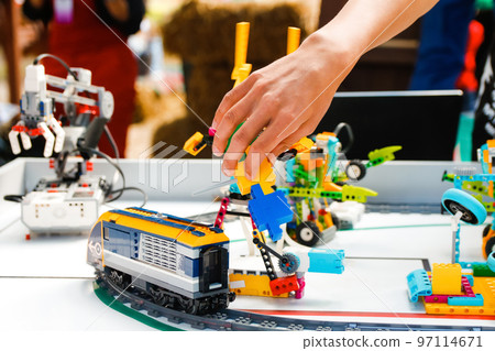 Defocus children hands holding ready made robots on table. Train an railway. Joyful smart whizzkid experimenting with humanoid robotic hand while developing his skills. Coding school. Out of focus Defocus children hands holding ready made robots on table. Train an railway. Joyful smart whizzkid experimenting with humanoid robotic hand while developing his skills. Coding school. Out of focus 97114671