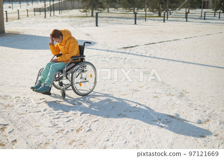 Woman crying in wheelchair outdoors in winter.  97121669