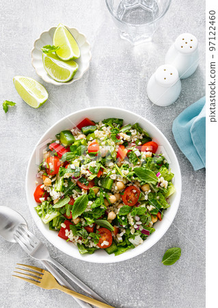 Tabbouleh salad. Tabouli salad with fresh parsley, onions, tomatoes, bulgur and chickpea. Healthy vegetarian food, mediterranean diet. Top view Tabbouleh salad. Tabouli salad with fresh parsley, onions, tomatoes, bulgur and chickpea. Healthy vegetarian food, mediterranean diet. Top view 97122460