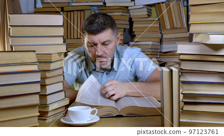 A bearded man reads a book in the library A bearded man reads a book in the library 97123761