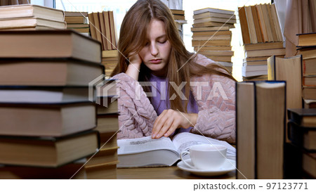 A girl reads a book in the library A girl reads a book in the library 97123771