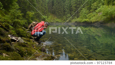 Bearded man with a backpack near a beautiful mountain lake Bearded man with a backpack near a beautiful mountain lake 97123784