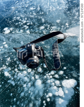 Professional photo camera on the ice of lake Baikal 97124580
