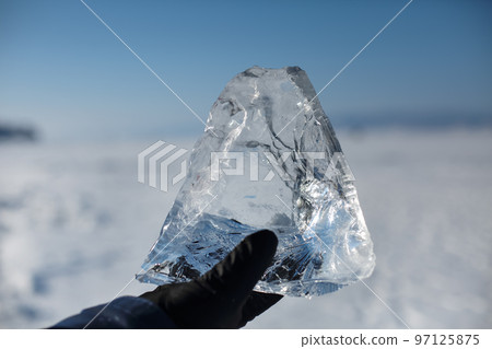 holding piece of transparent crushed ice cubes in his hands 97125875