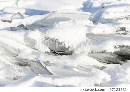 Pieces of ice lying on the ideal smooth ice of baikal with ice hummocks in the horizon 97125881