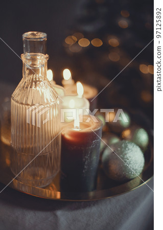 New Year's still life. Glasses and a decanter from transparent glass, candles and golden xmas ball New Year's still life. Glasses and a decanter from transparent glass, candles and golden xmas ball 97125892