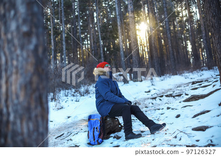 Traveller man in a blue winter jacket ad red cap in the woods. Sandy bay, Baikal lake, winter time 97126327