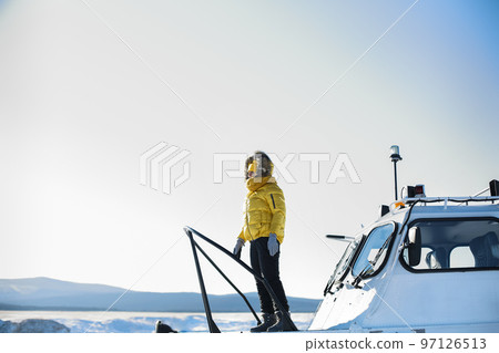 Beautiful winter landscape. Woman in yellow jacket stading on the khivus. Ice travel in winter holidays Beautiful winter landscape. Woman in yellow jacket stading on the khivus. Ice travel in winter holidays 97126513