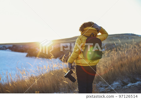 Female traveller looking to Baikal lake in winter time. Woman holding professional camera Female traveller looking to Baikal lake in winter time. Woman holding professional camera 97126514