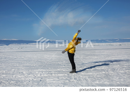 Woman in a bright yellow jacket pours boiling water from a thermos that turns into a halo a ball over her head Woman in a bright yellow jacket pours boiling water from a thermos that turns into a halo a ball over her head 97126516