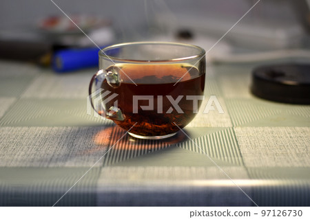 A glass cup of tea is on the table. 97126730