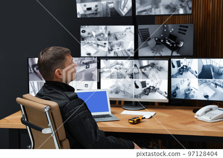 Security guard monitoring modern CCTV cameras indoors Security guard monitoring modern CCTV cameras indoors 97128404