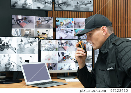 Security guard using portable transmitter at workplace in office Security guard using portable transmitter at workplace in office 97128410