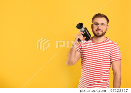 Young man with vintage video camera on yellow background, space for text Young man with vintage video camera on yellow background, space for text 97128527