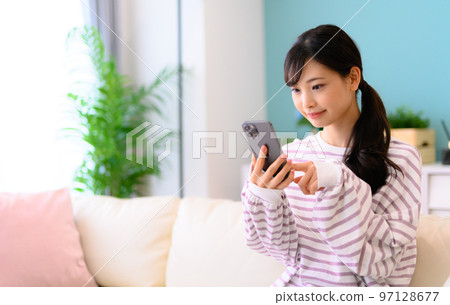 Woman operating a smartphone Woman operating a smartphone 97128677