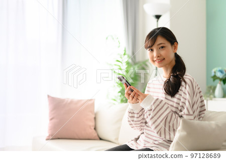 Woman operating a smartphone Woman operating a smartphone 97128689