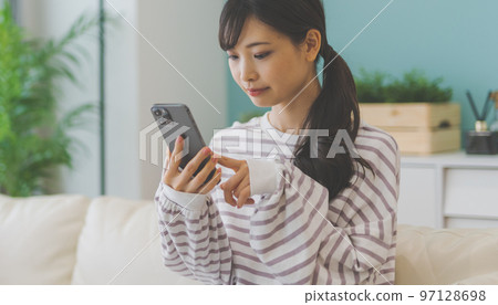 Woman operating a smartphone Woman operating a smartphone 97128698