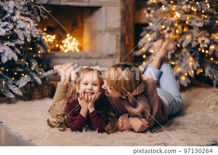 Mom and daughter in a decorated Christmas living room at home Mom and daughter in a decorated Christmas living room at home 97130264