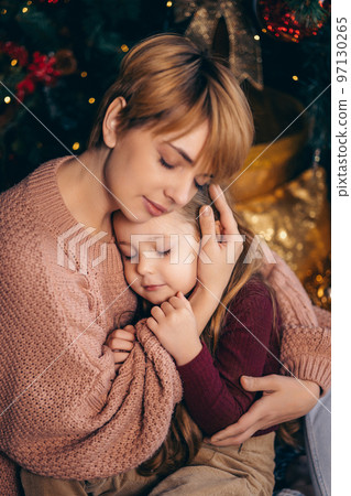 Mom and daughter in a decorated Christmas living room at home Mom and daughter in a decorated Christmas living room at home 97130265