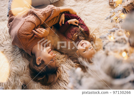 Mom and daughter in a decorated Christmas living room at home Mom and daughter in a decorated Christmas living room at home 97130266
