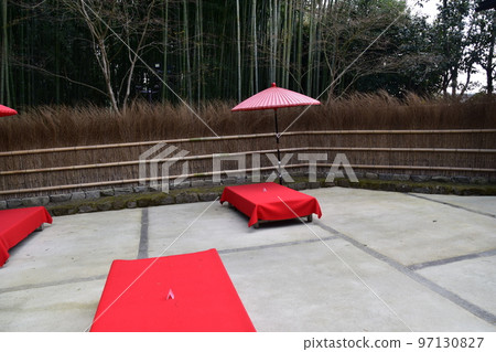 Kyoto, Japan, tea house, bamboo fence, and surrounding bamboo grove, bench covered with red cloth called floor bench, and red umbrella Kyoto, Japan, tea house, bamboo fence, and surrounding bamboo grove, bench covered with red cloth called floor bench, and red umbrella 97130827