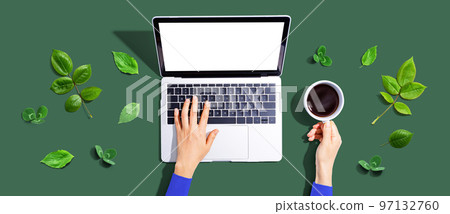 Person using a laptop computer with green leaves 97132760