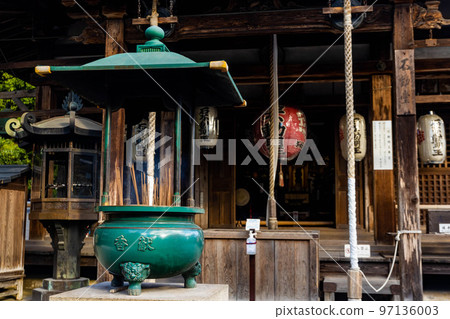 Pot with incense sticks burning at the buddhist shrine 97136003