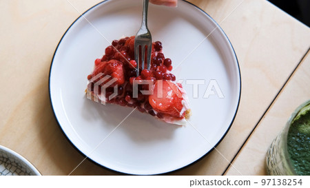 Hand of female taking berries from the top of piece of natural organic vegan pie, slow motion. View from the top 97138254