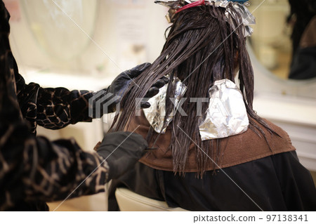 Male hairdresser applying drug to woman's hair Male hairdresser applying drug to woman's hair 97138341