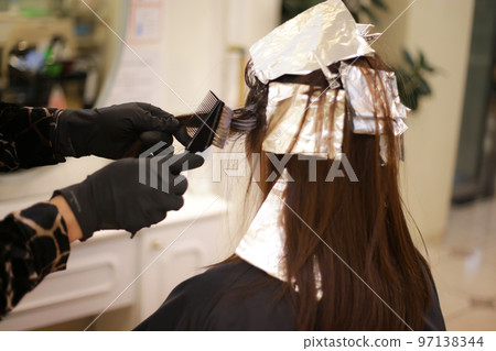 Male hairdresser applying drug to woman's hair Male hairdresser applying drug to woman's hair 97138344